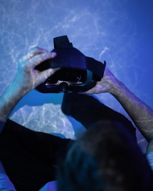Close-up of a professional Wild Rift player's hands intensely controlling their mobile device during a crucial tournament moment. The screen displays a vibrant and chaotic team fight scene. The player's focused expression conveys the high stakes and dedication involved in competitive gaming.