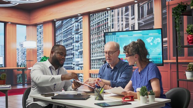 A diverse group of business professionals in a modern office looking at financial projections on a large screen, symbolizing corporate strategy adjustment to new tax laws.