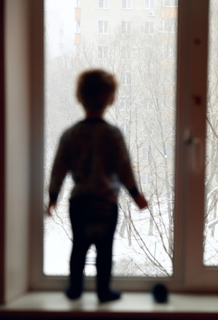 A depiction of a solitary teenager looking out a window, with a subtle melancholic expression, highlighting feelings of isolation in adolescence.