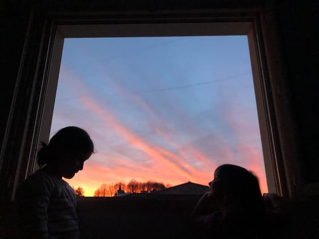 A person looking out a window at a sunrise or sunset, with a sense of calm and hope, perhaps holding a cup of tea or coffee. The image should convey resilience and the quiet strength of overcoming challenges, with soft, ambient lighting.